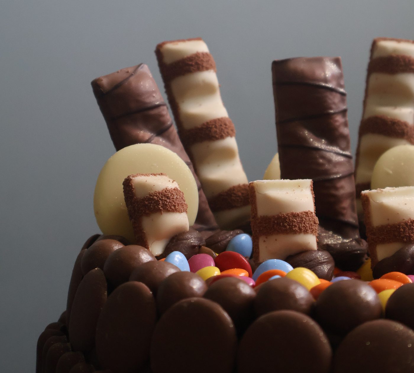 Close-up of Kinder bars and white chocolate buttons standing in a ring of chocolate buttons filled with Smarties