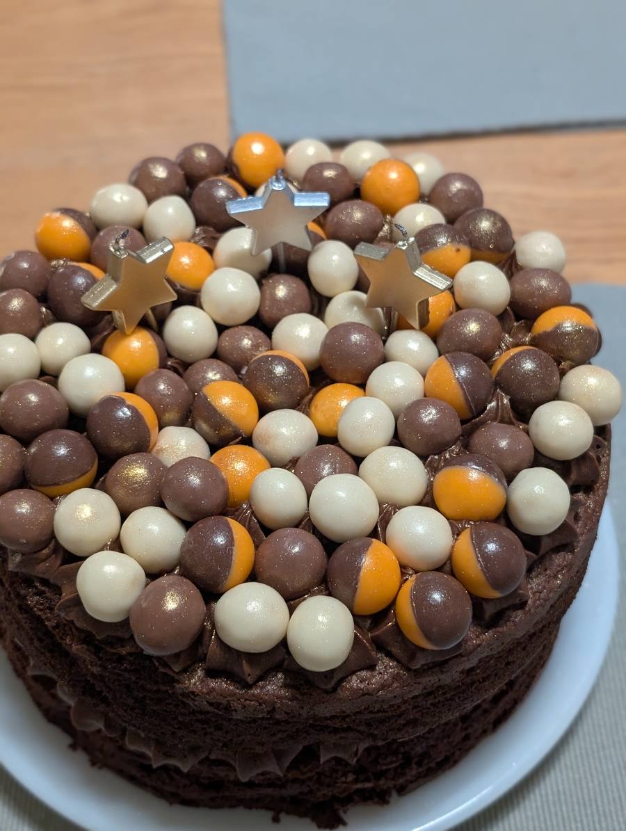 Chocolate cake topped with orange, white and milk chocolate sphere sprinkles